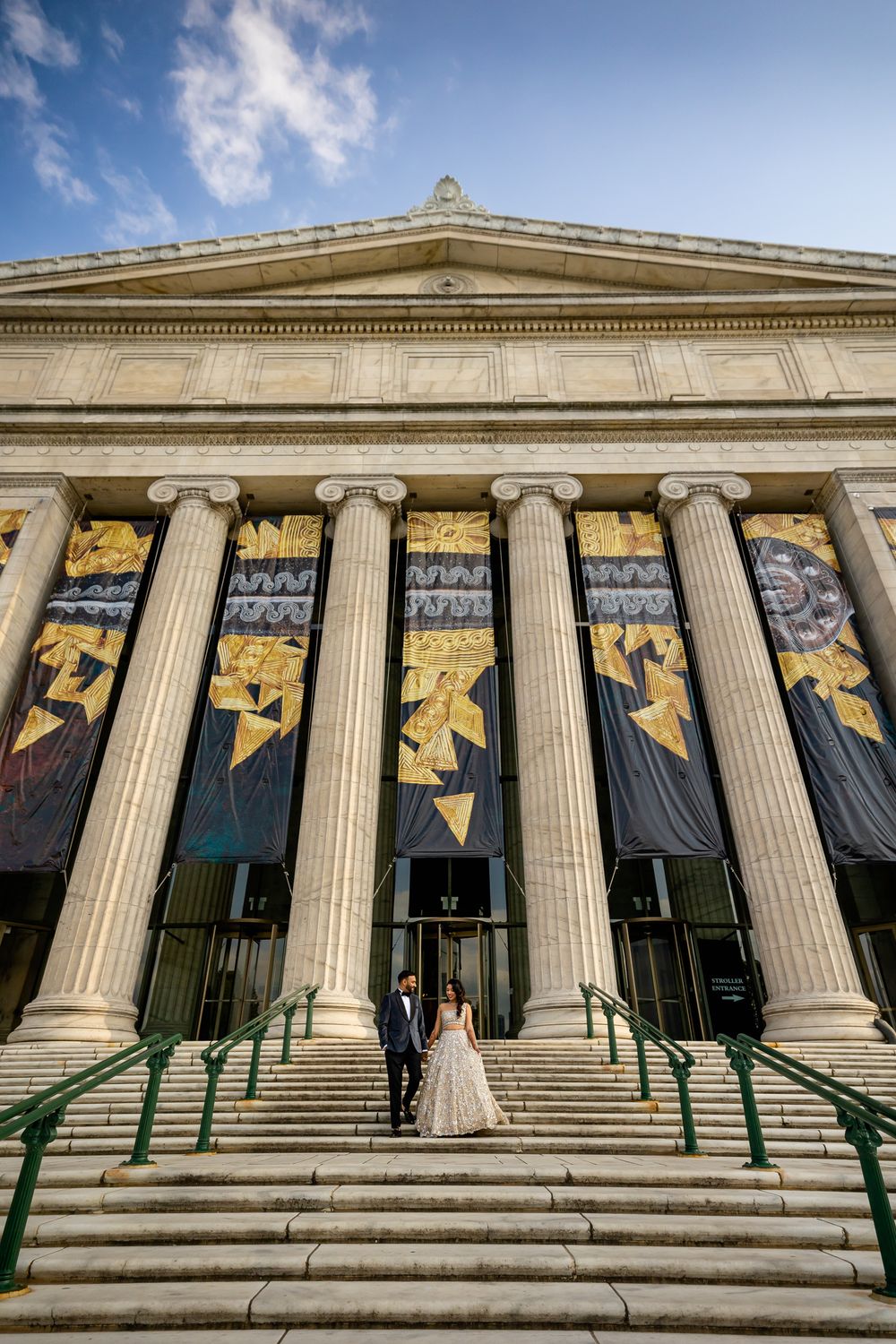 Neoclassical museum building entrance with grand stone columns and decorative banners hanging between pillars.