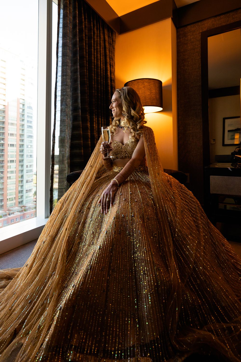 A stunning gold sequined ball gown with a voluminous skirt glimmers in warm lighting near a window.