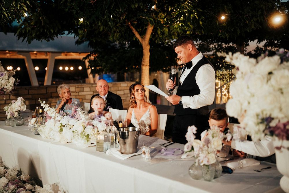 Long tables decorated with floral centerpieces and candles at an elegant outdoor wedding reception.