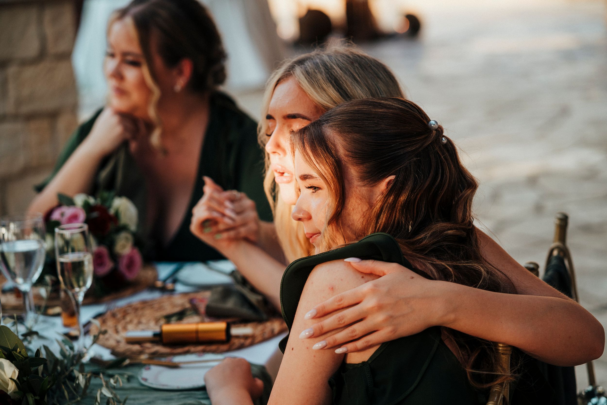 Guests enjoying a candlelit outdoor dinner party at sunset with warm lighting and wine glasses on the table.