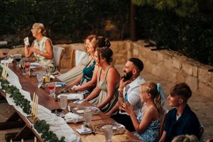 Guests enjoying an outdoor dinner party at a long rustic table in the evening.