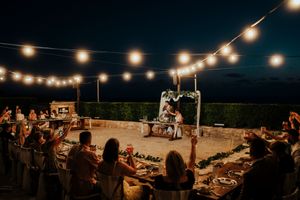 String lights illuminate an outdoor evening reception with tables set up under the night sky.