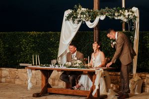 Rustic outdoor wedding reception setup with wooden tables and string lights creating a warm ambiance.