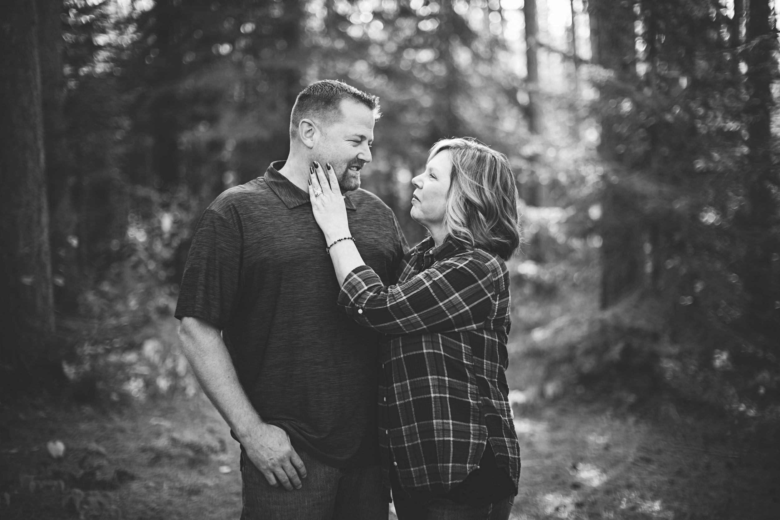 A couple embraces intimately in a black and white forest setting, with multiple romantic poses shown in sequence.