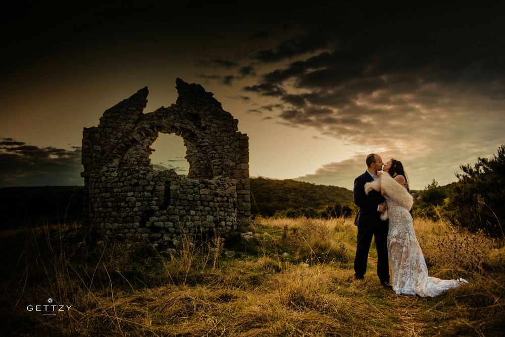 A romantic silhouette at sunset near stone castle ruins in a golden meadow landscape.