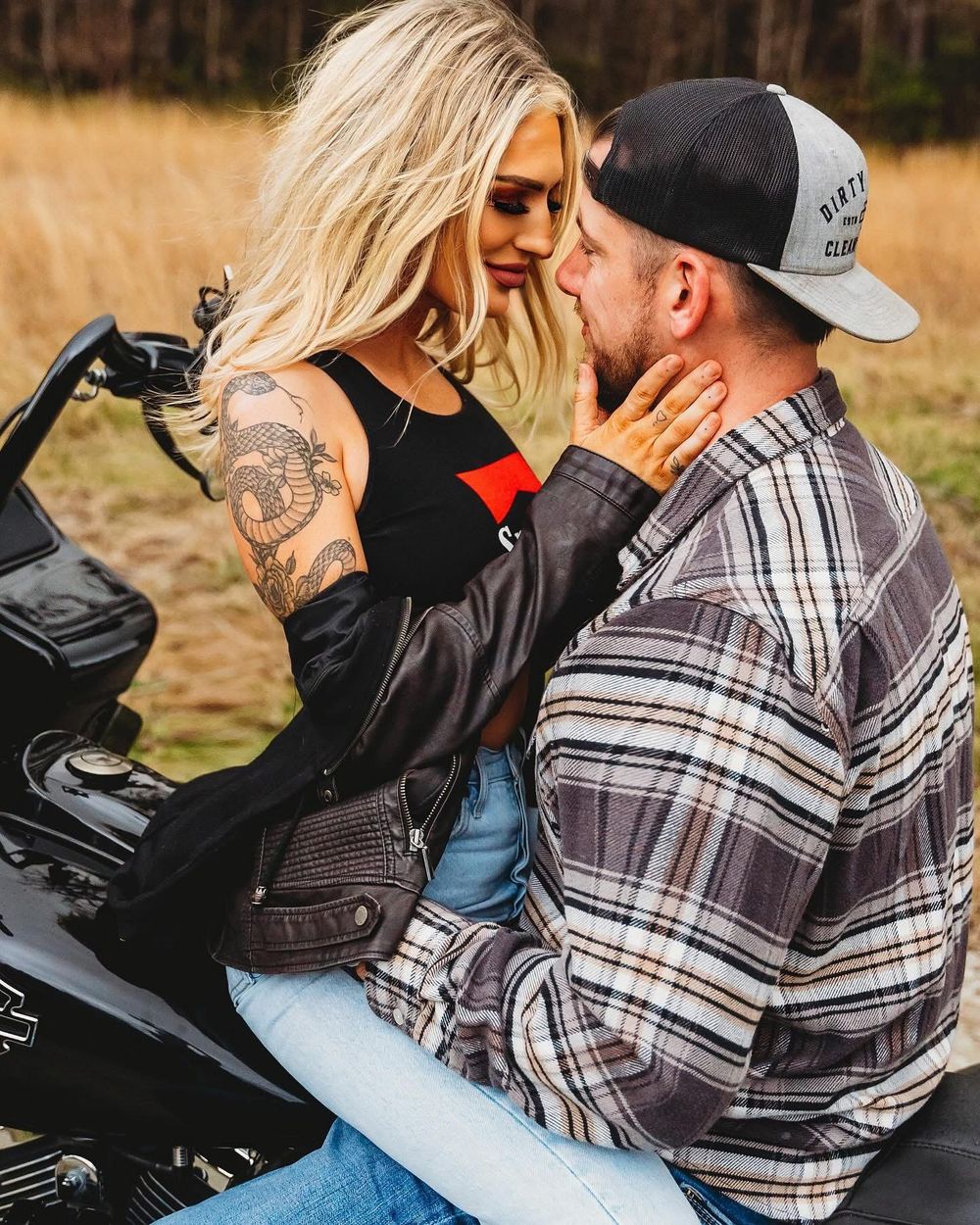 Romantic couple sharing an intimate moment together while sitting on a motorcycle outdoors.