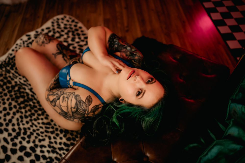 Intimate portrait on leopard print rug with dramatic lighting and visible body art.
