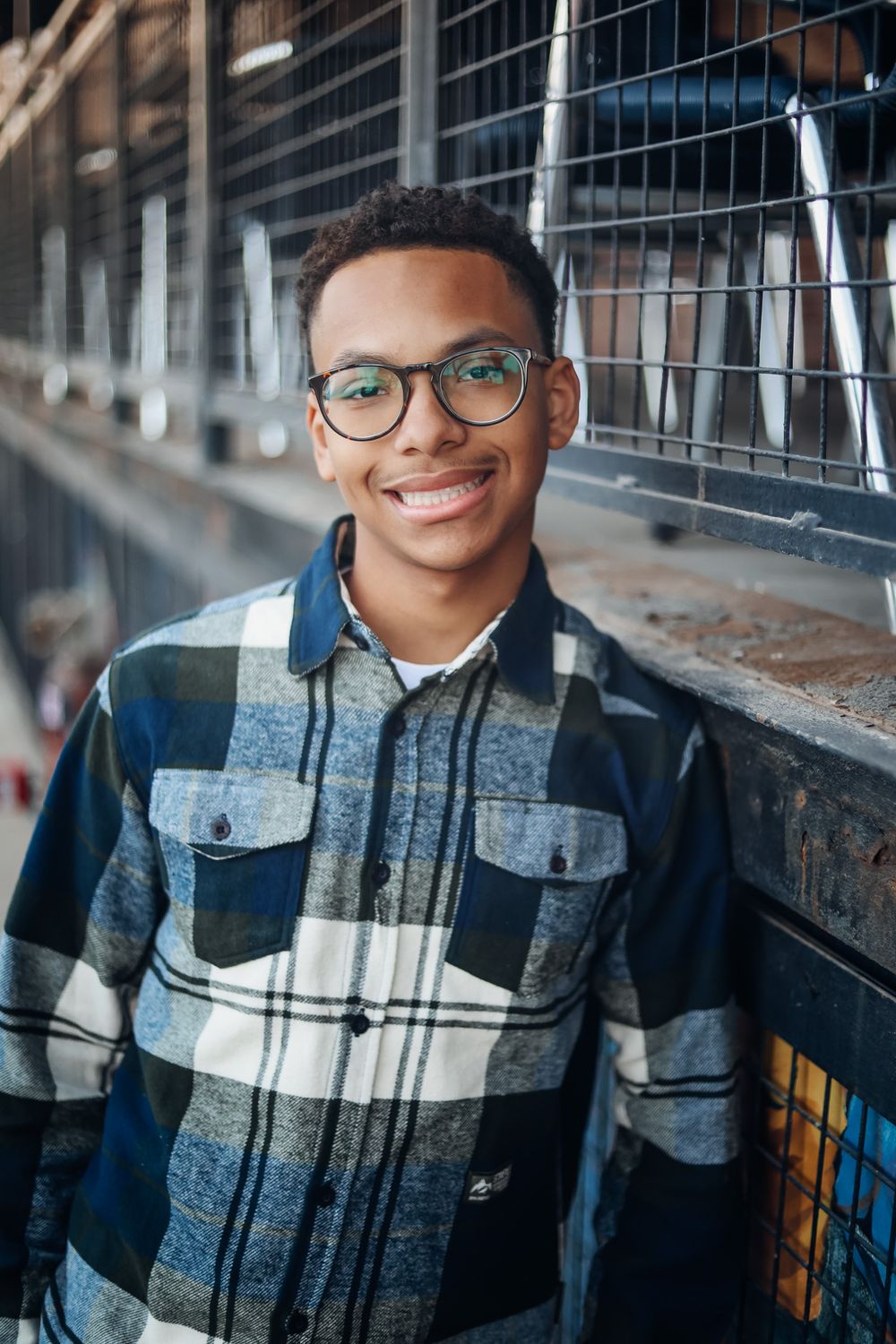 A series of four photos showing someone wearing a plaid jacket and glasses against an urban background.