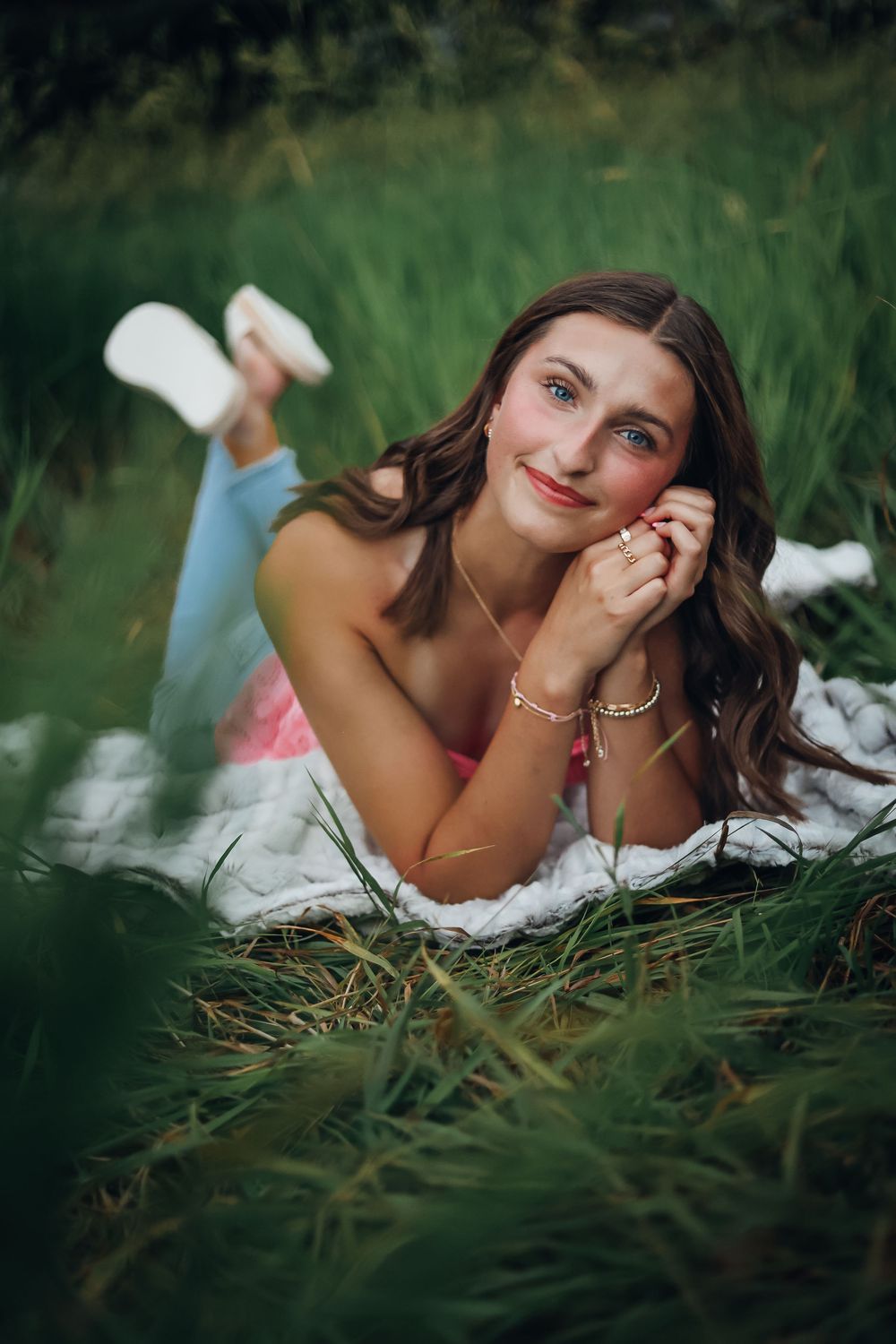 Woman laying in tall grass during outdoor photo session. Senior photography