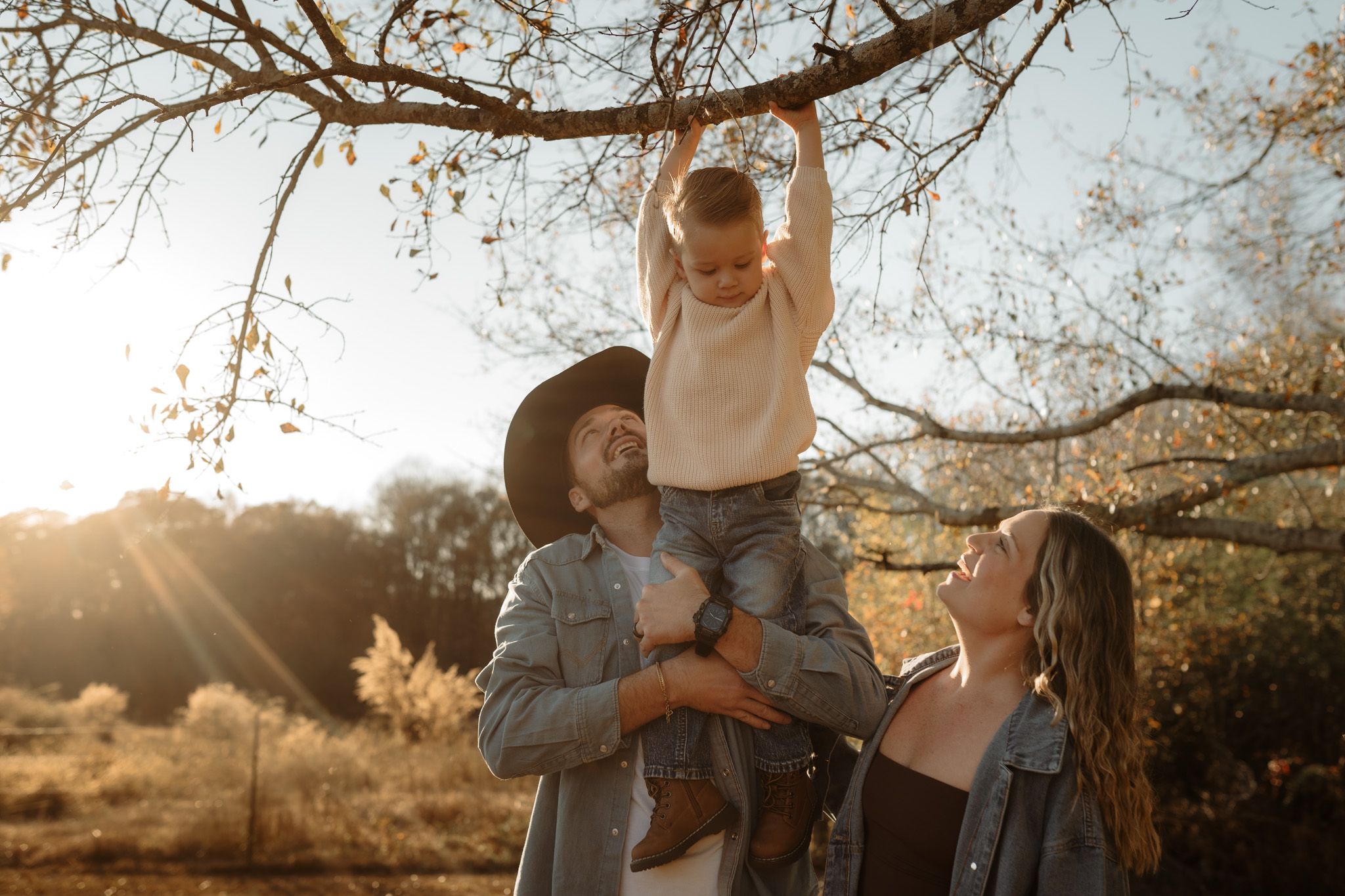 Family gathering under bare tree branches during sunset in autumn.
