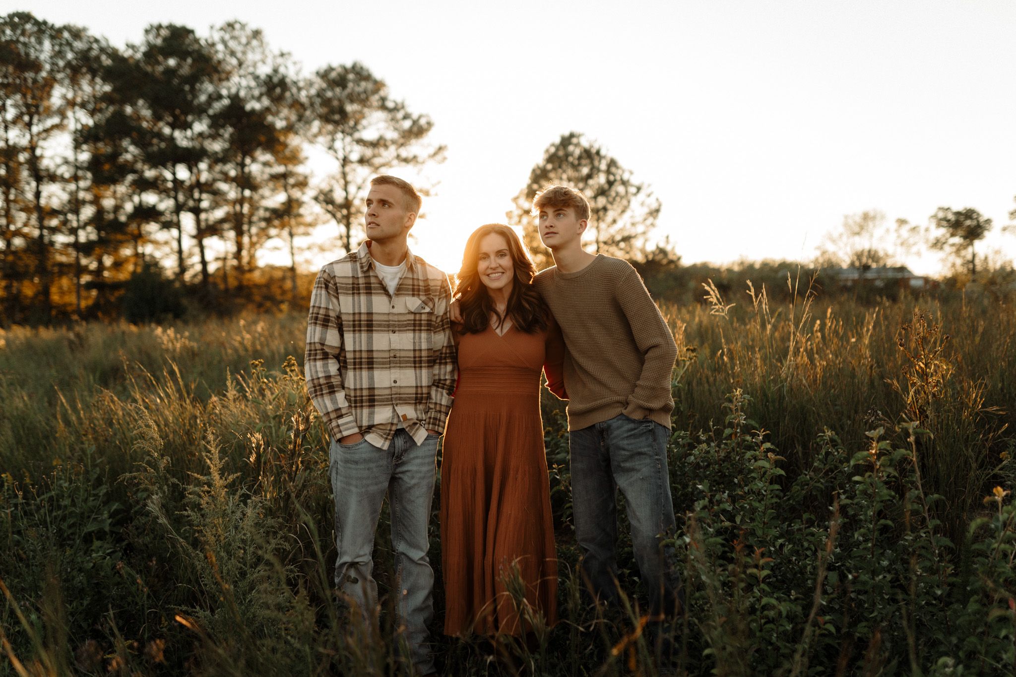 Family posing together in rustic outdoor setting during sunset.