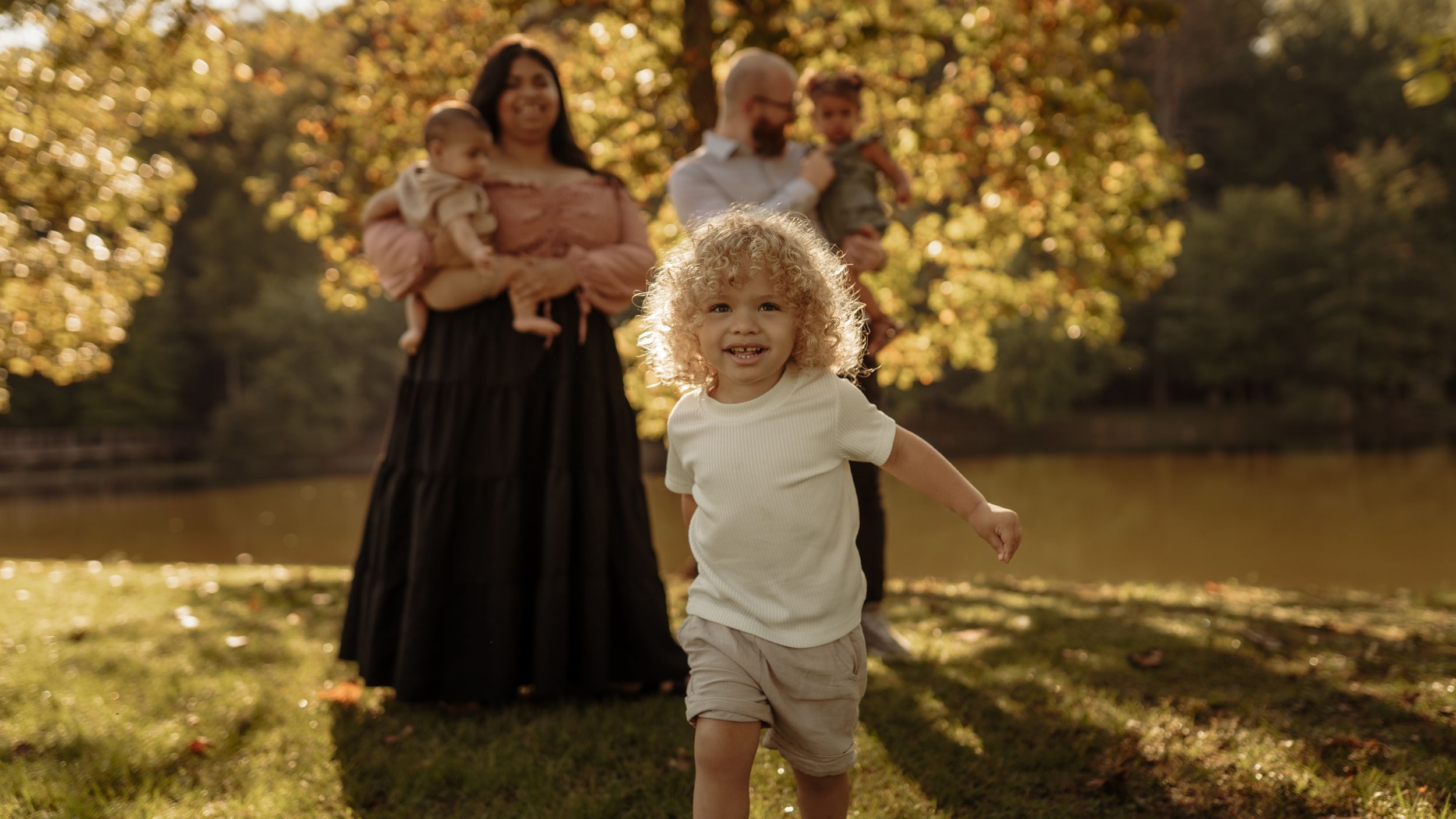 Family enjoying a golden sunset together in a park during an autumn photoshoot.