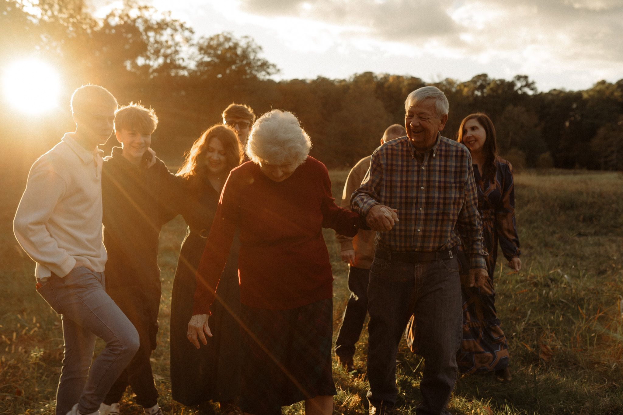 Group walking together through a field at golden hour with sun flare.