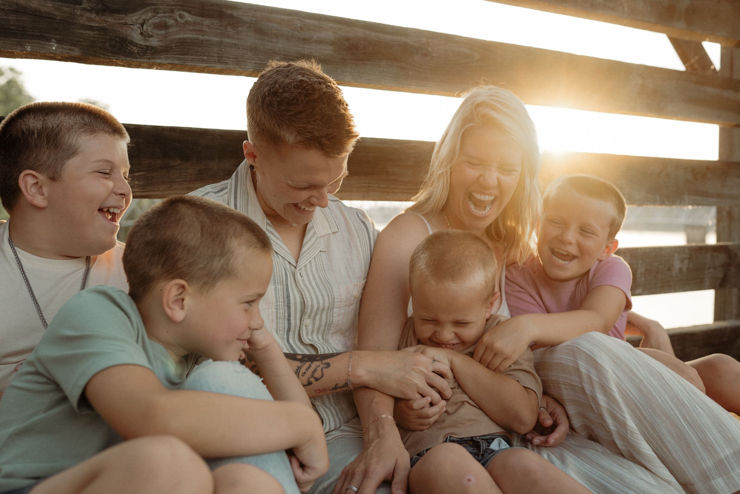 Tender family moments captured in warm sunlight through wooden beams.