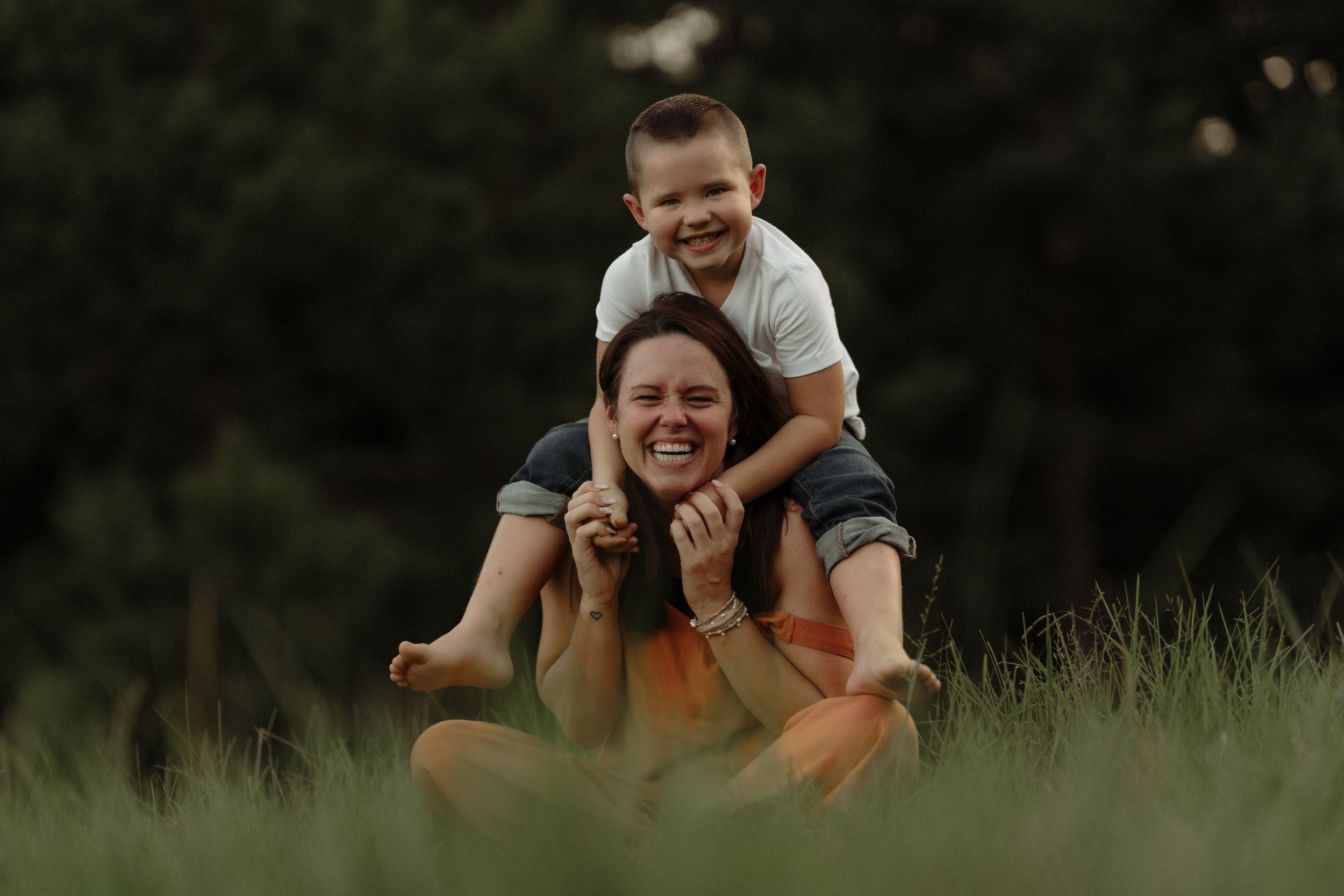 Playful moments captured on grass during outdoor family photography session.