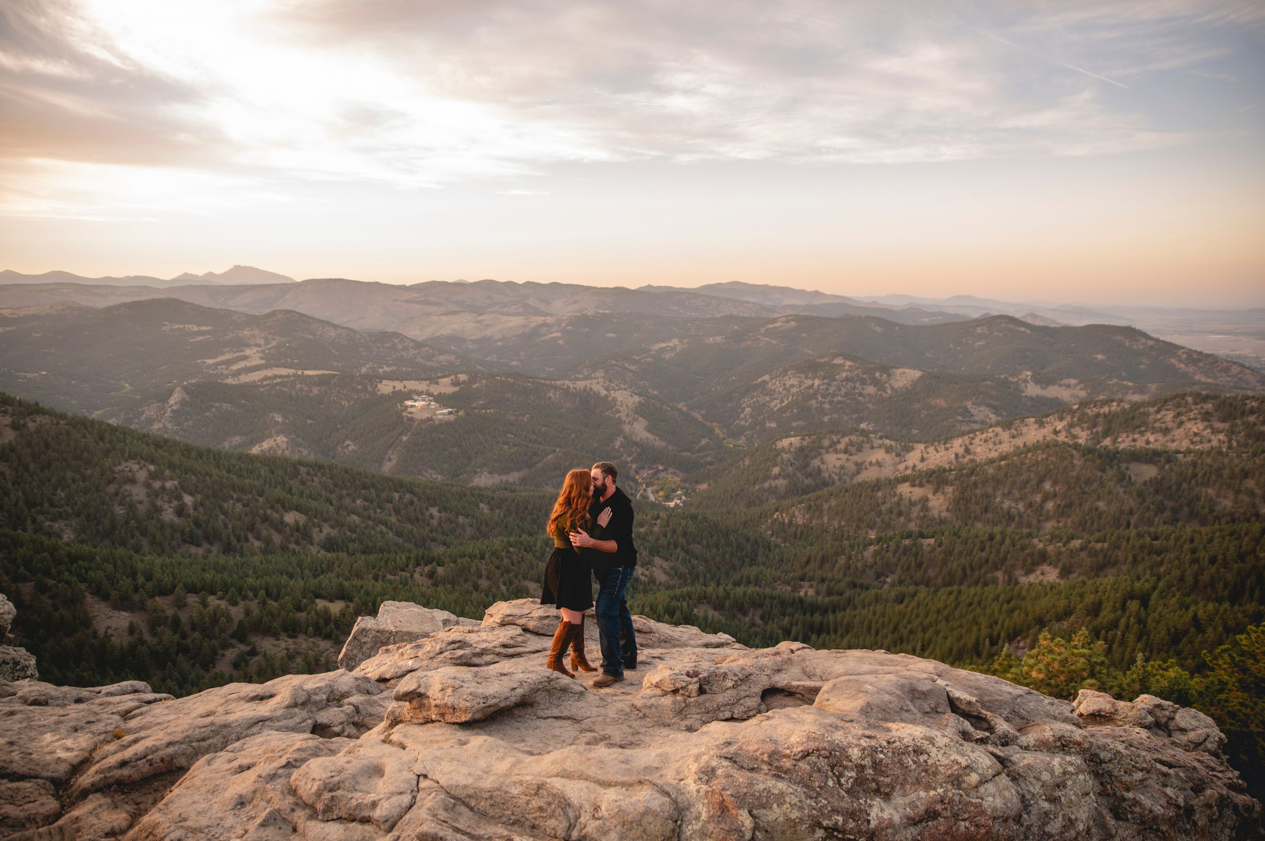 A romantic mountain-top embrace during sunset overlooking a vast Colorado landscape.