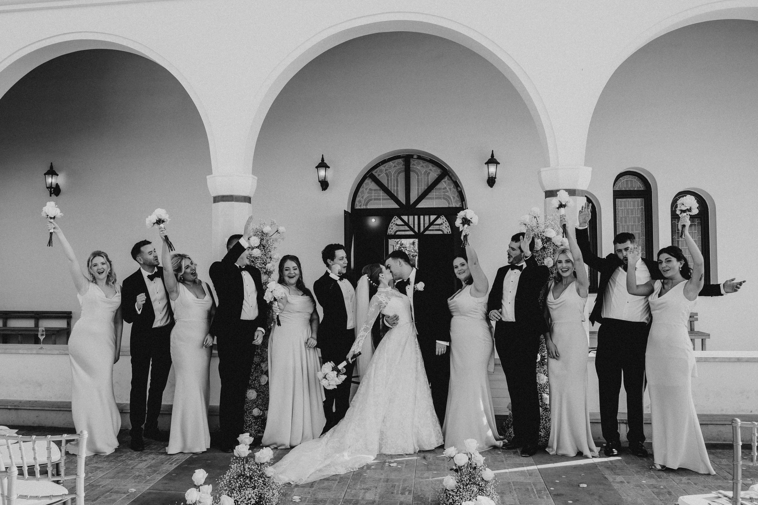 A black and white photo sequence showing a wedding party posing under arched columns of a building.