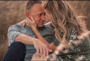 Romantic couple sharing an intimate moment outdoors in a golden field, woman tenderly holding man's face.