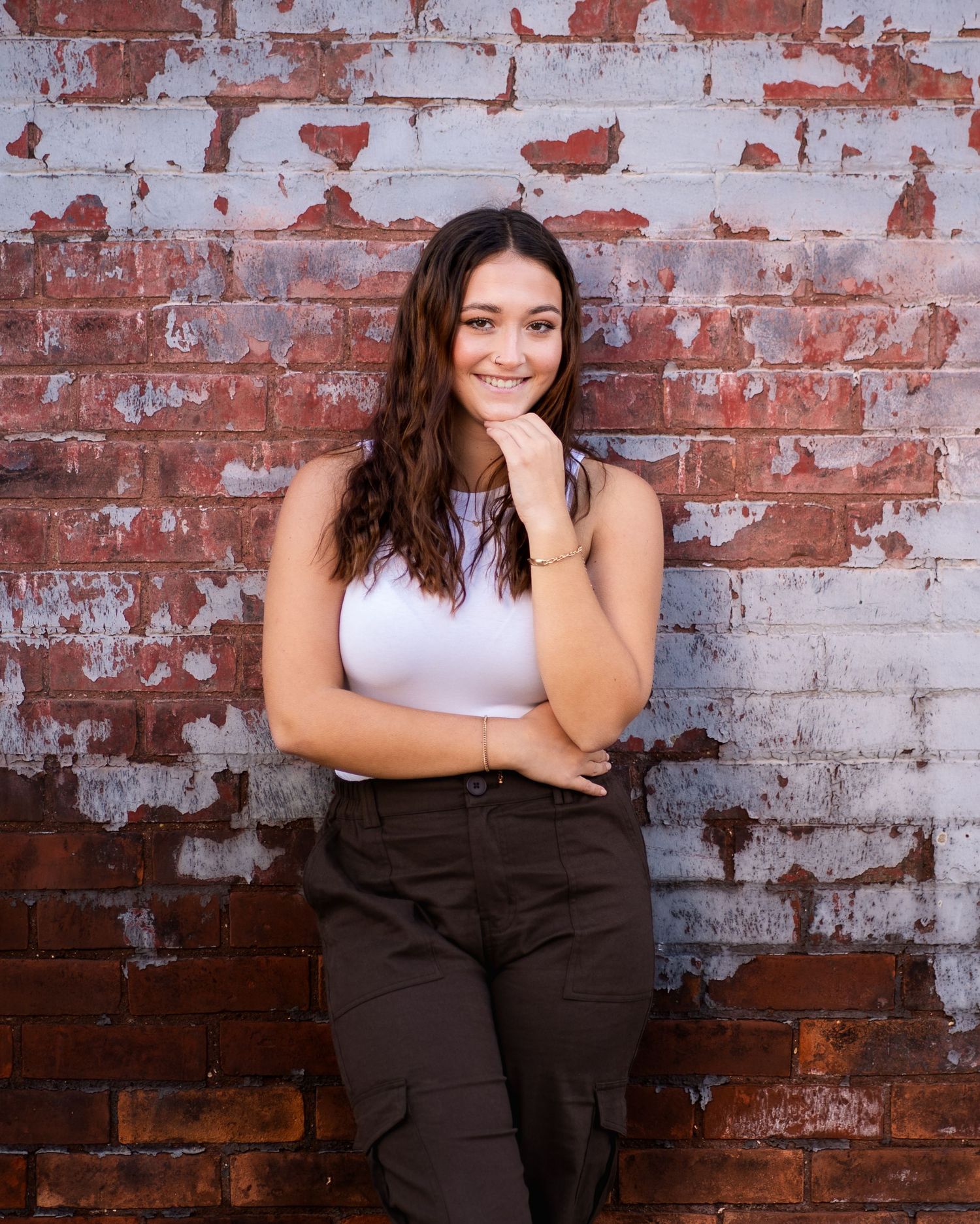 Urban portrait session against a weathered red brick wall with peeling paint texture.