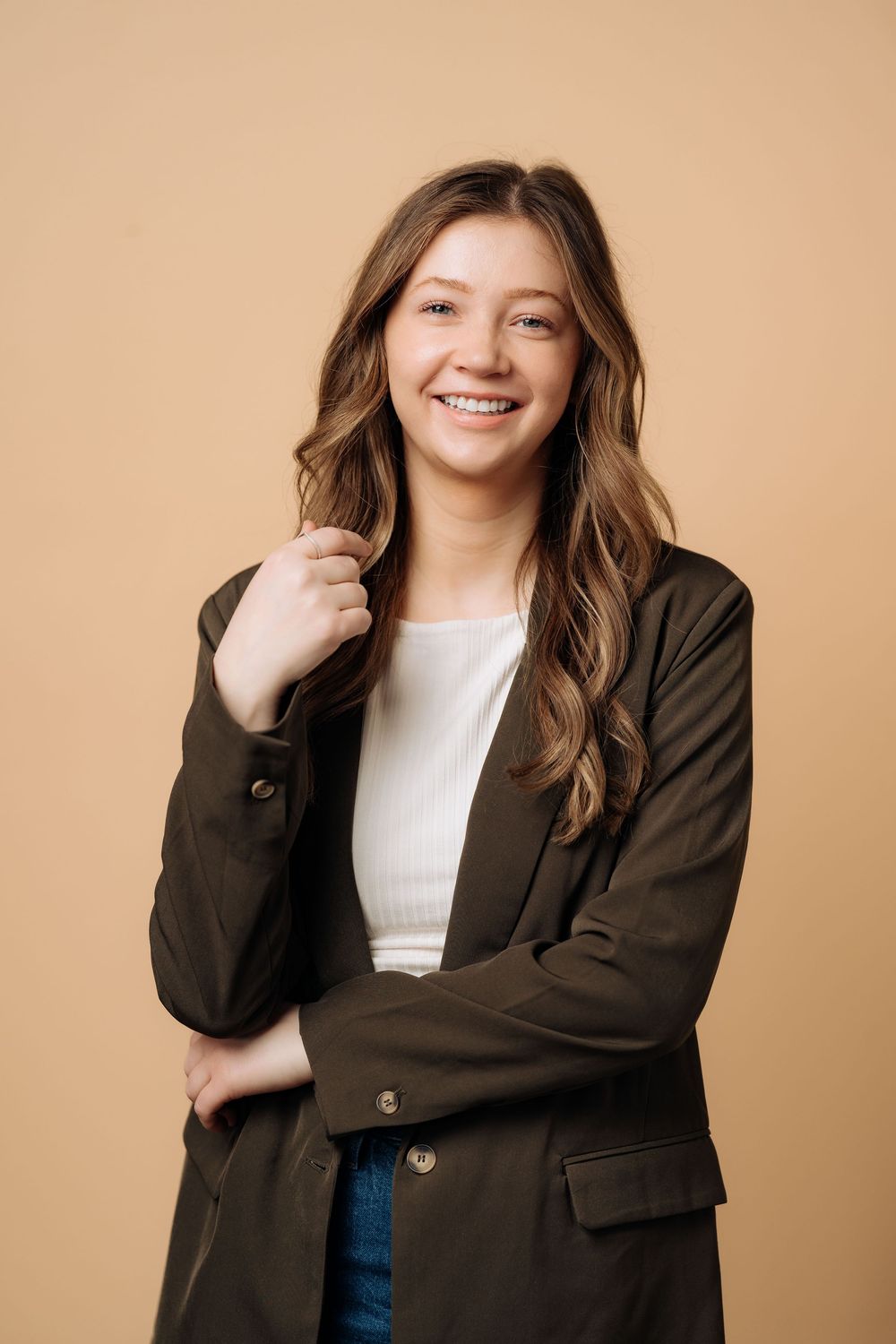 Professional studio portrait series showing warm expressions wearing a brown blazer against a beige background.