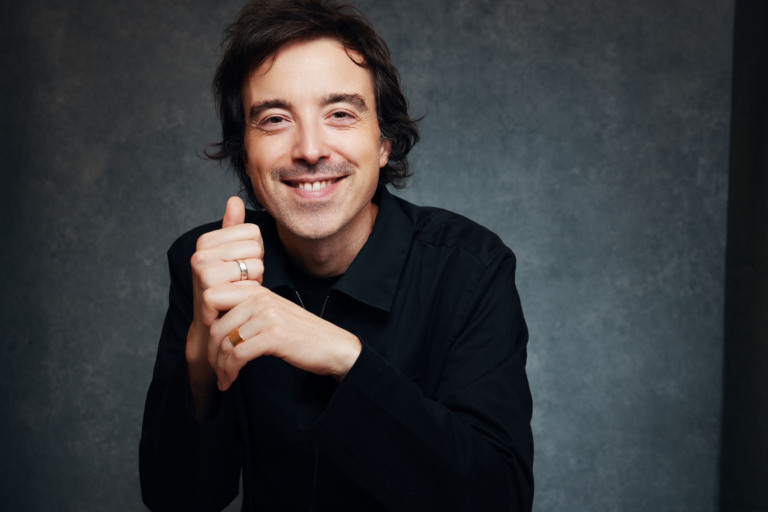 Professional headshot series showing the italian singer Diodato in a black sweater against dark background