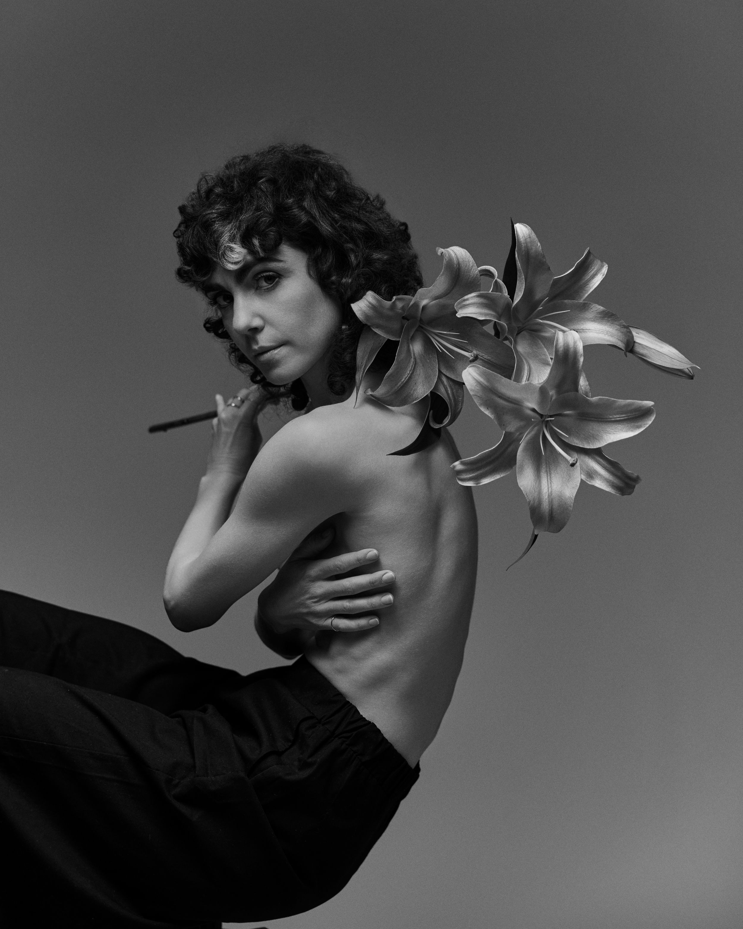 Artistic black and white portrait series featuring elegant poses with white lilies against dark background.