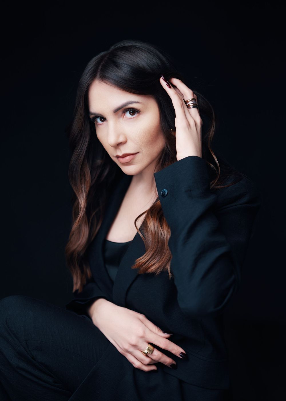 A series of dark moody portrait photographs showing a person in a black sweater against a black background.