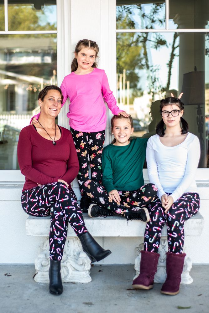 Four people wearing coordinated outfits sit together on a white porch step.