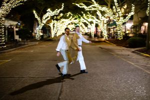Two figures dancing under illuminated trees at night.
