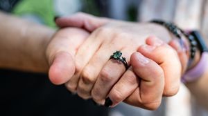 A close-up sequence showing hands gently touching and holding fingers in various intimate poses against a blurred background.