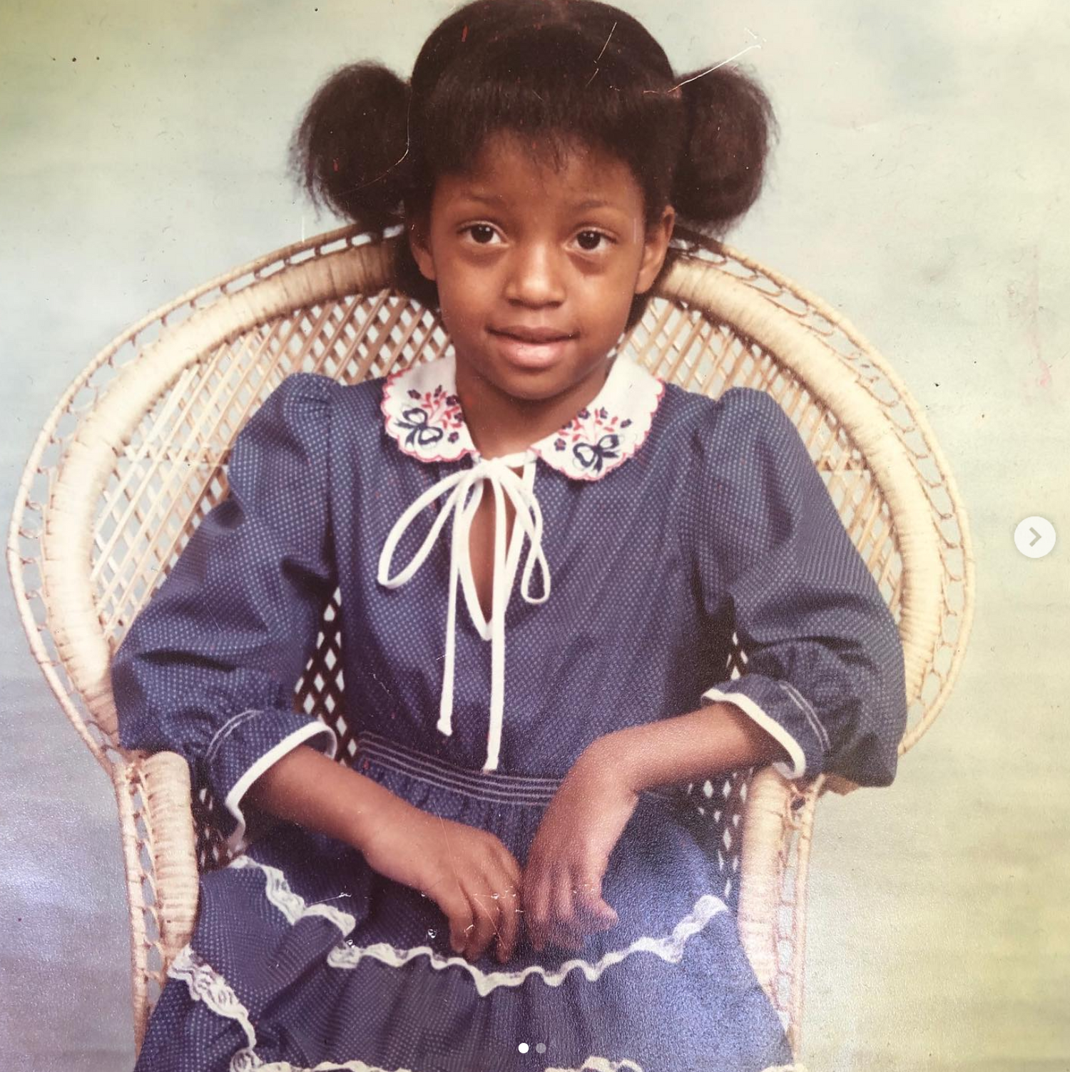 Vintage style photos of young child in navy blue dress with white lace collar sitting in wicker chair.