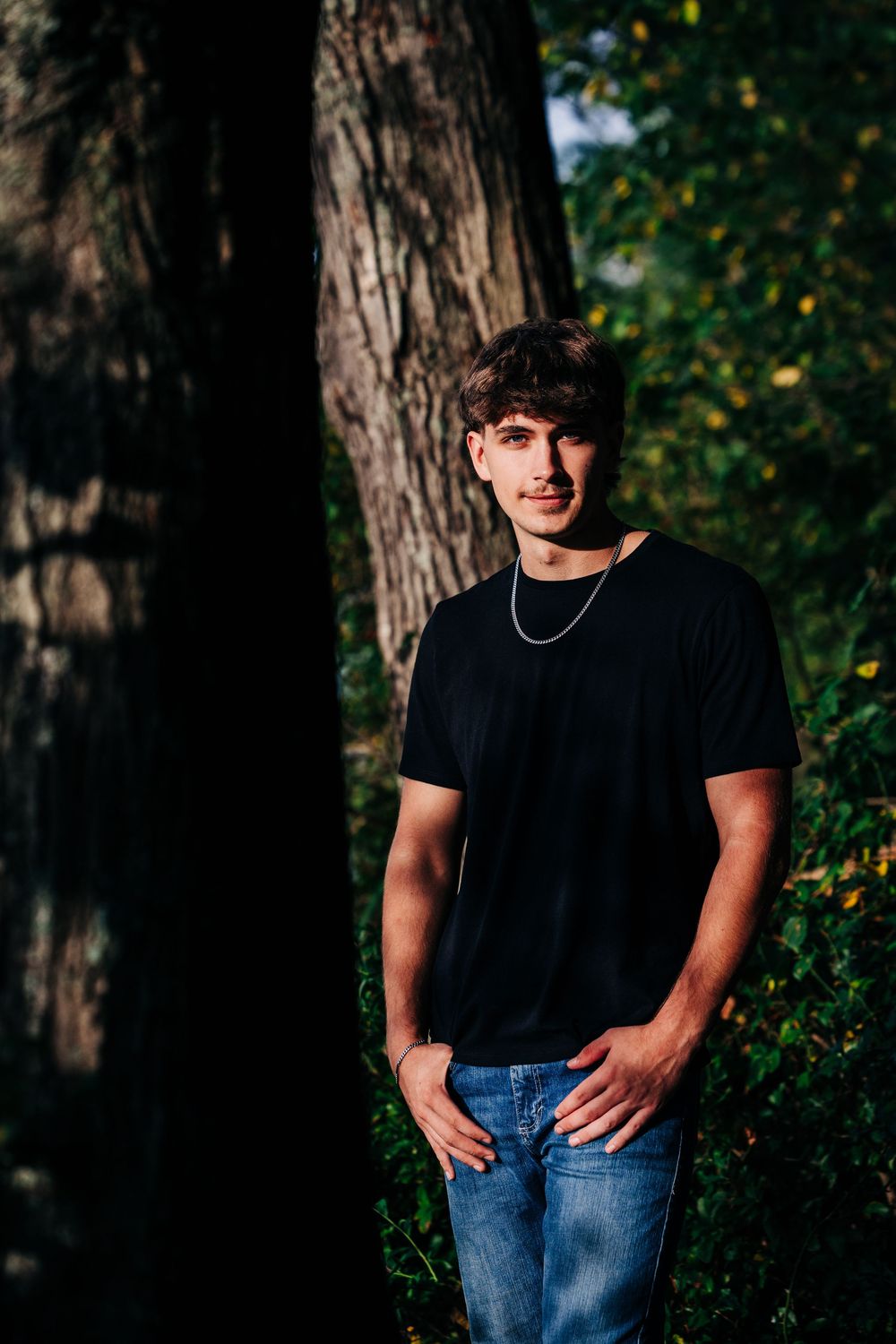 Moody outdoor portrait series showing person in black t-shirt and jeans against tree backdrop in natural lighting.