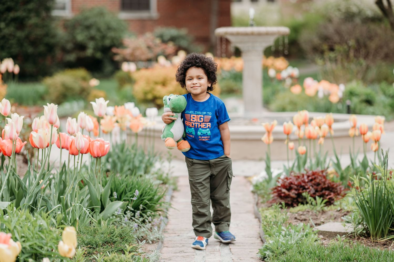 A young child runs joyfully along a garden path bordered by beautiful spring tulips in bloom in Montclair.