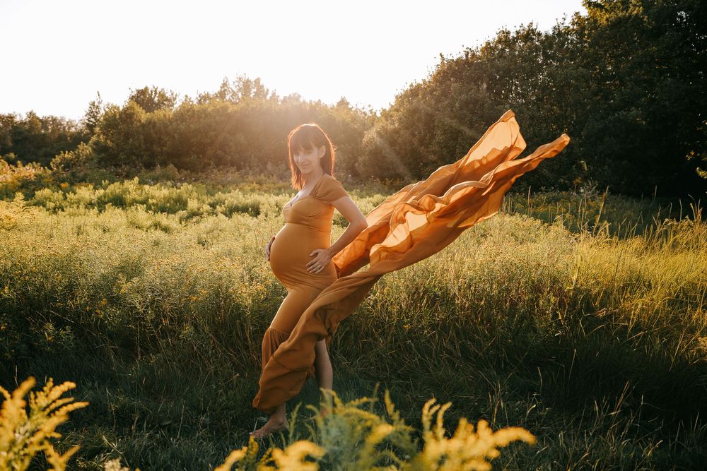 A silhouetted figure stands in a golden sunlit field with arms outstretched during sunset.