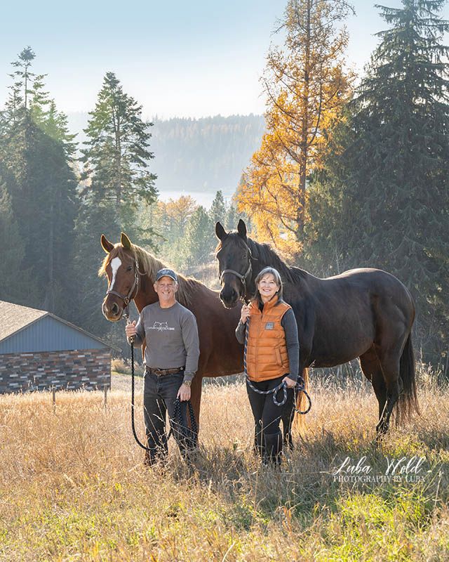 Hayden family portrait of husband and wife with two horses with view of the lake by Post Falls photographer Luba Wold