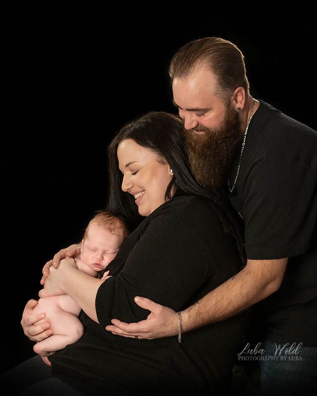 studio portrait of family with a newborn baby boy on a black background by photographer Luba Wold