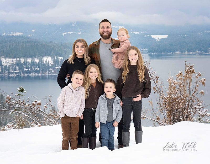 winter family portrait of seven with a view of Hayden Lake by photographer Luba Wold