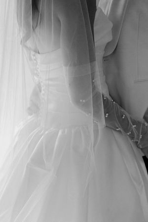 Intricate detail of back of bride in strapless white wedding dress with lace gloves embracing groom by wedding photographer August and Vine