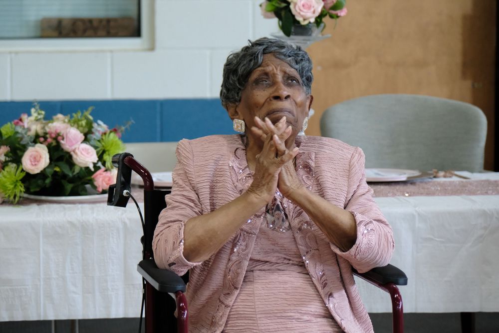 Woman in pink attire seated at decorated table during celebratory event.