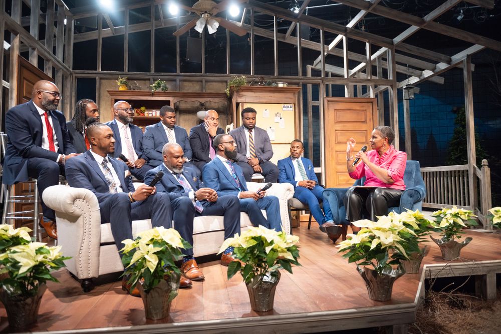 Panel discussion setup on stage with potted plants and rustic decor.