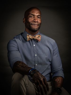 Portrait series in formal attire with navy suit and patterned bow tie against dark background.