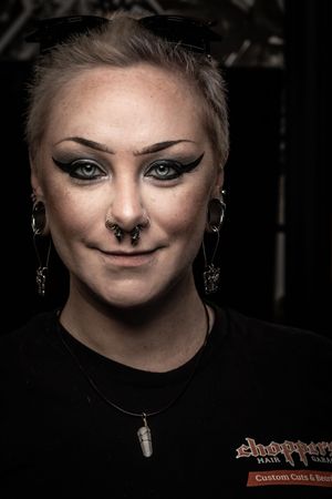 A sequence of dark portraits showing someone wearing black clothing and facial jewelry against a dark background.