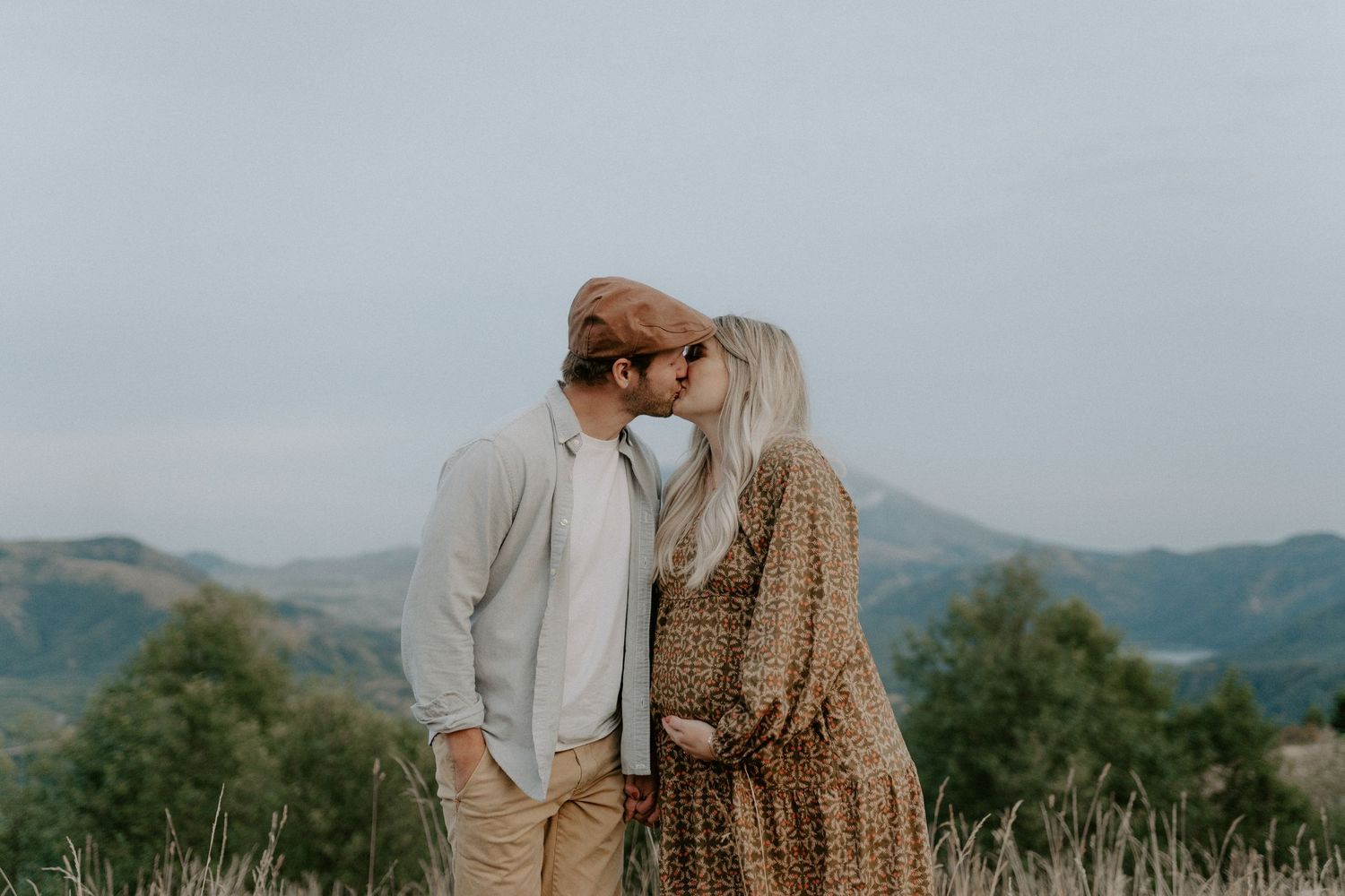 A romantic moment between two people in cozy sweaters against a mountain backdrop.