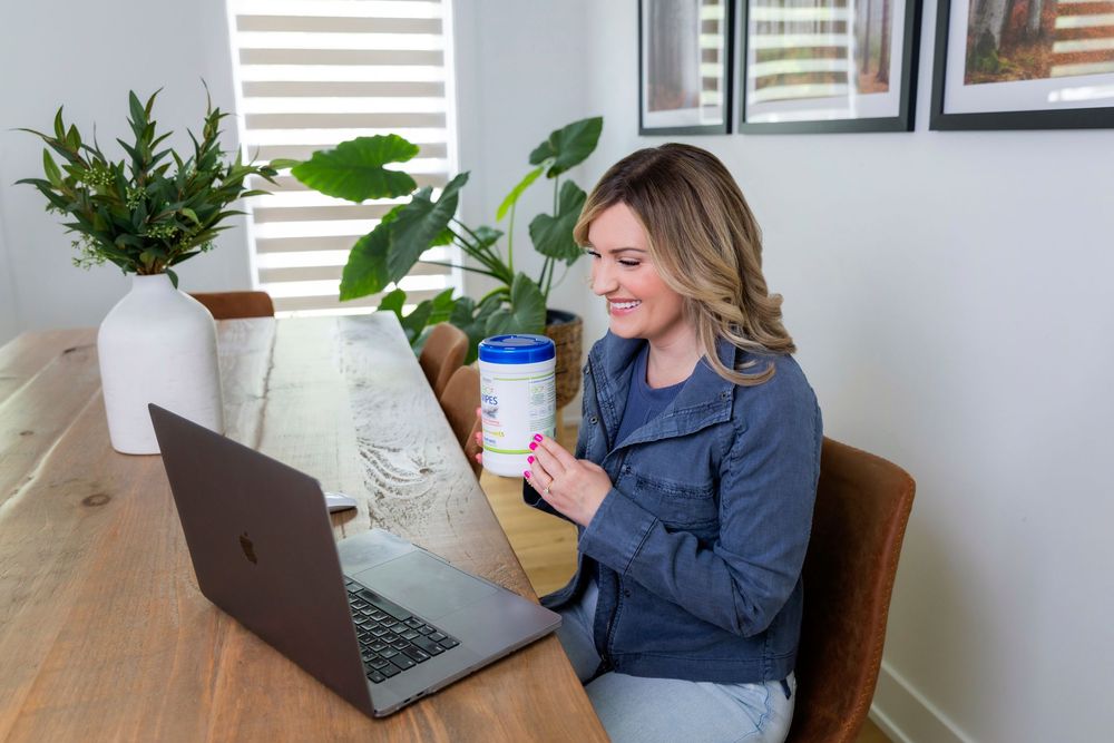 Professional working at a modern home office desk with laptop, plants and natural lighting.