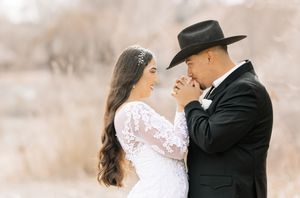 happy married couple holding hands and looking at eachother tenderly as she wearing a wedding dress and he wears a tuxedo posing for a pictu