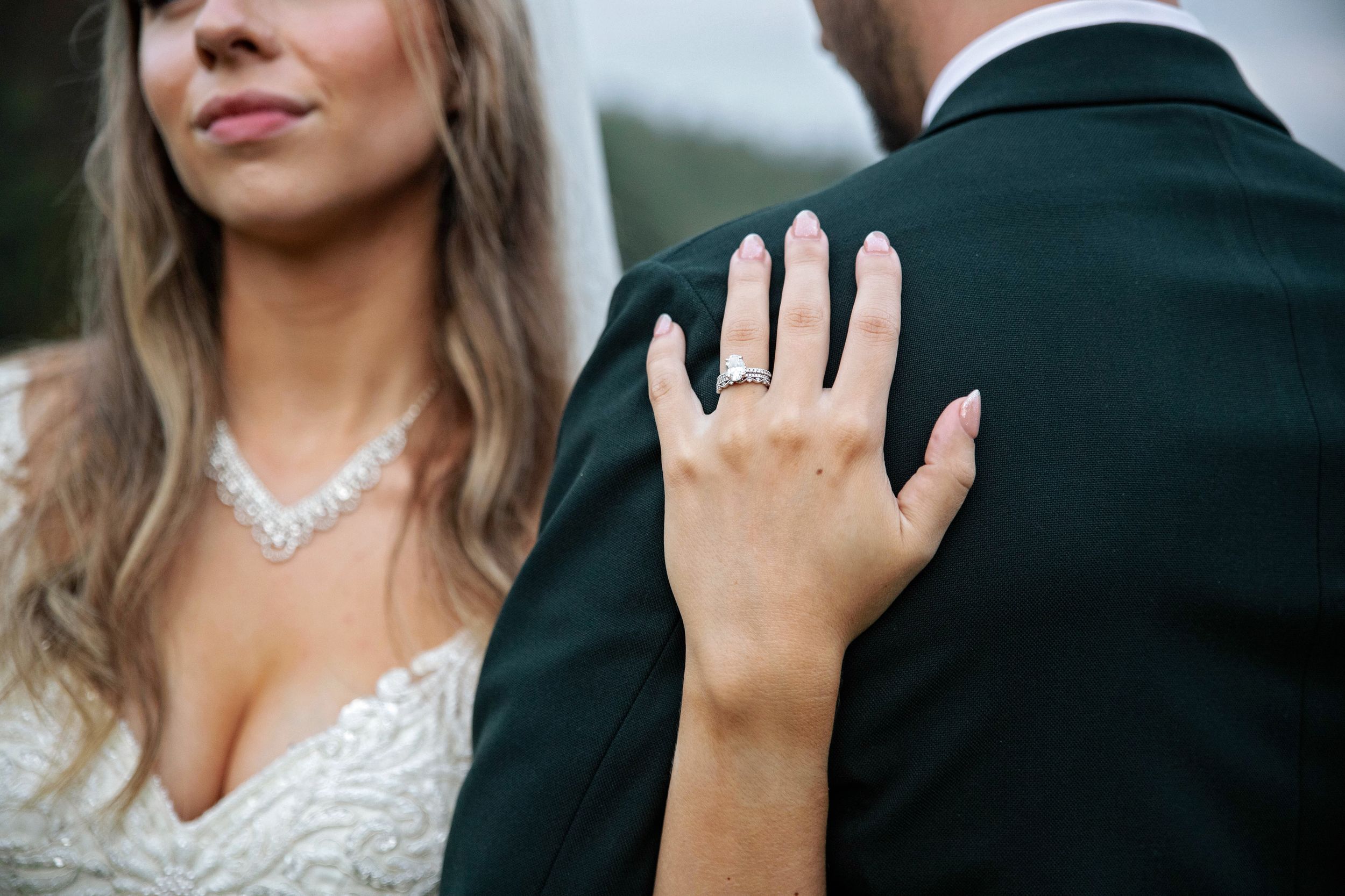 A close-up shot of hands wearing elegant wedding rings during a romantic outdoor ceremony.