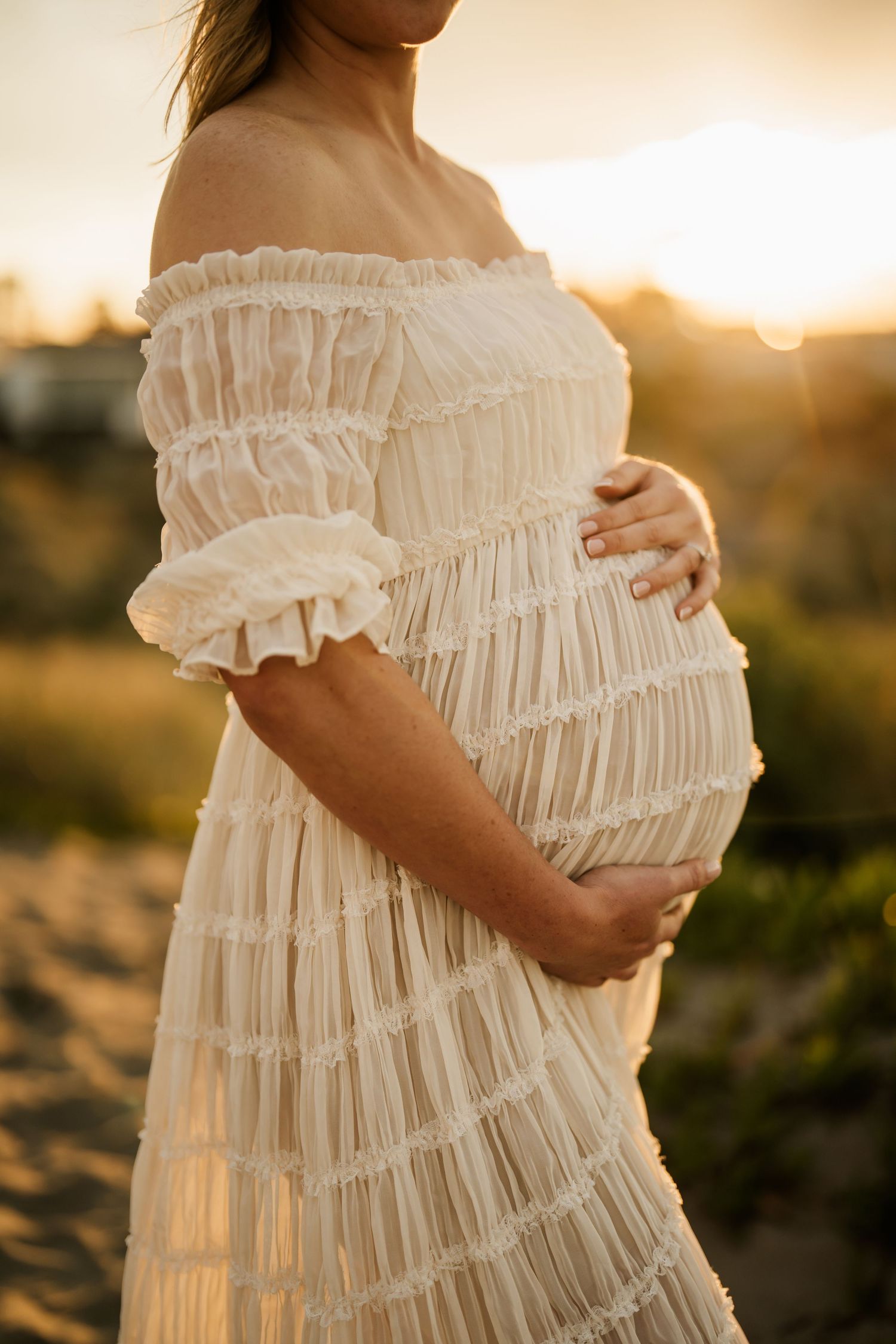 Pregnant mother holding her baby bump during a sunset maternity photography session