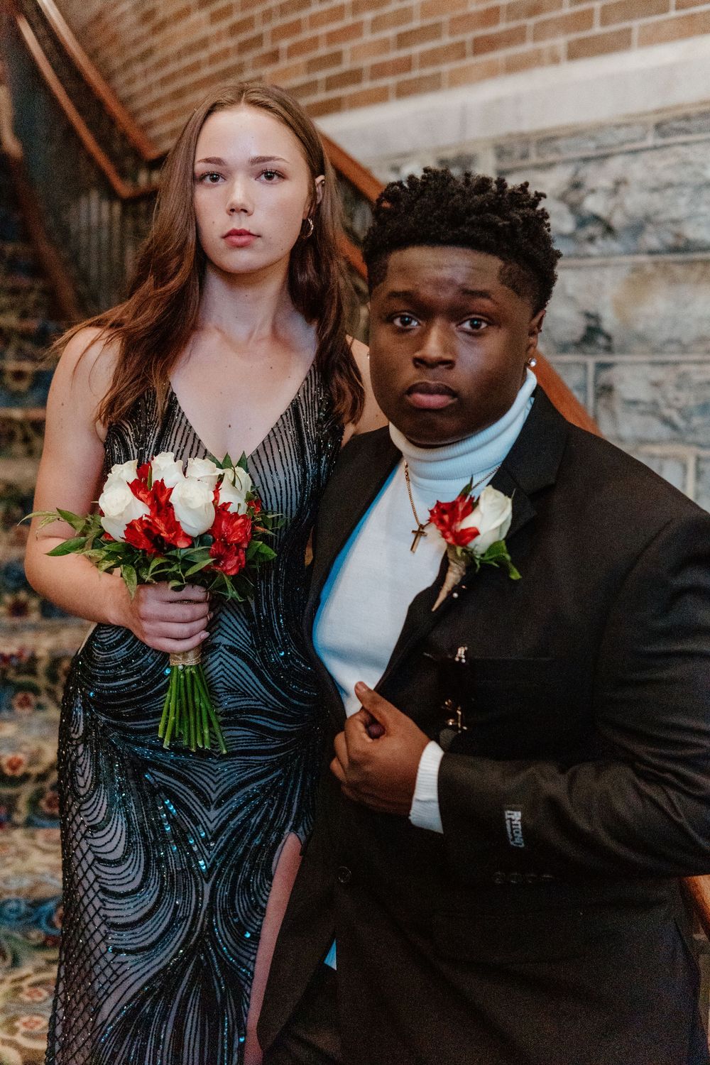 Formal couple posing on stone steps with bouquet and boutonniere.