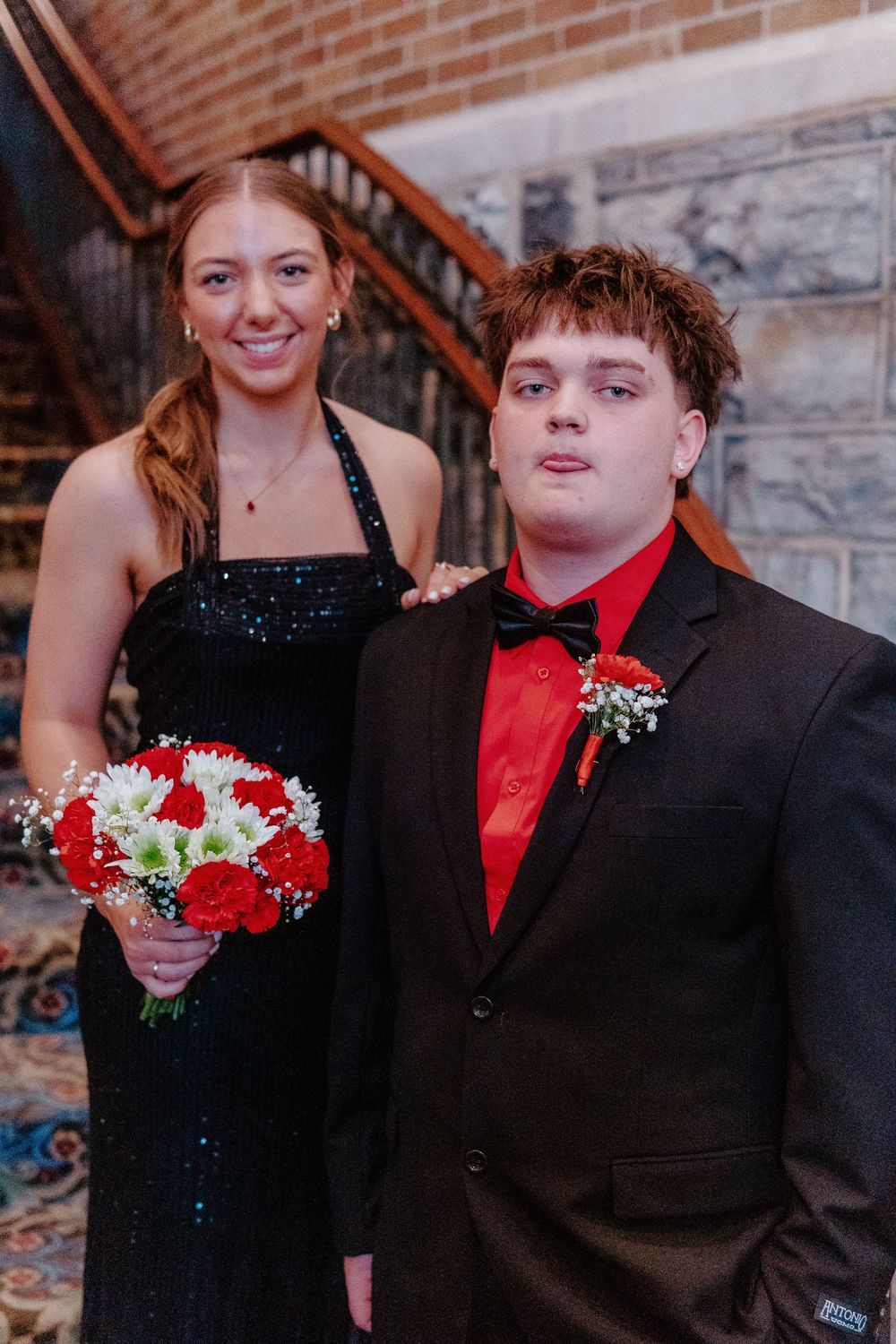 Formal couple posing together on stairs at an event.