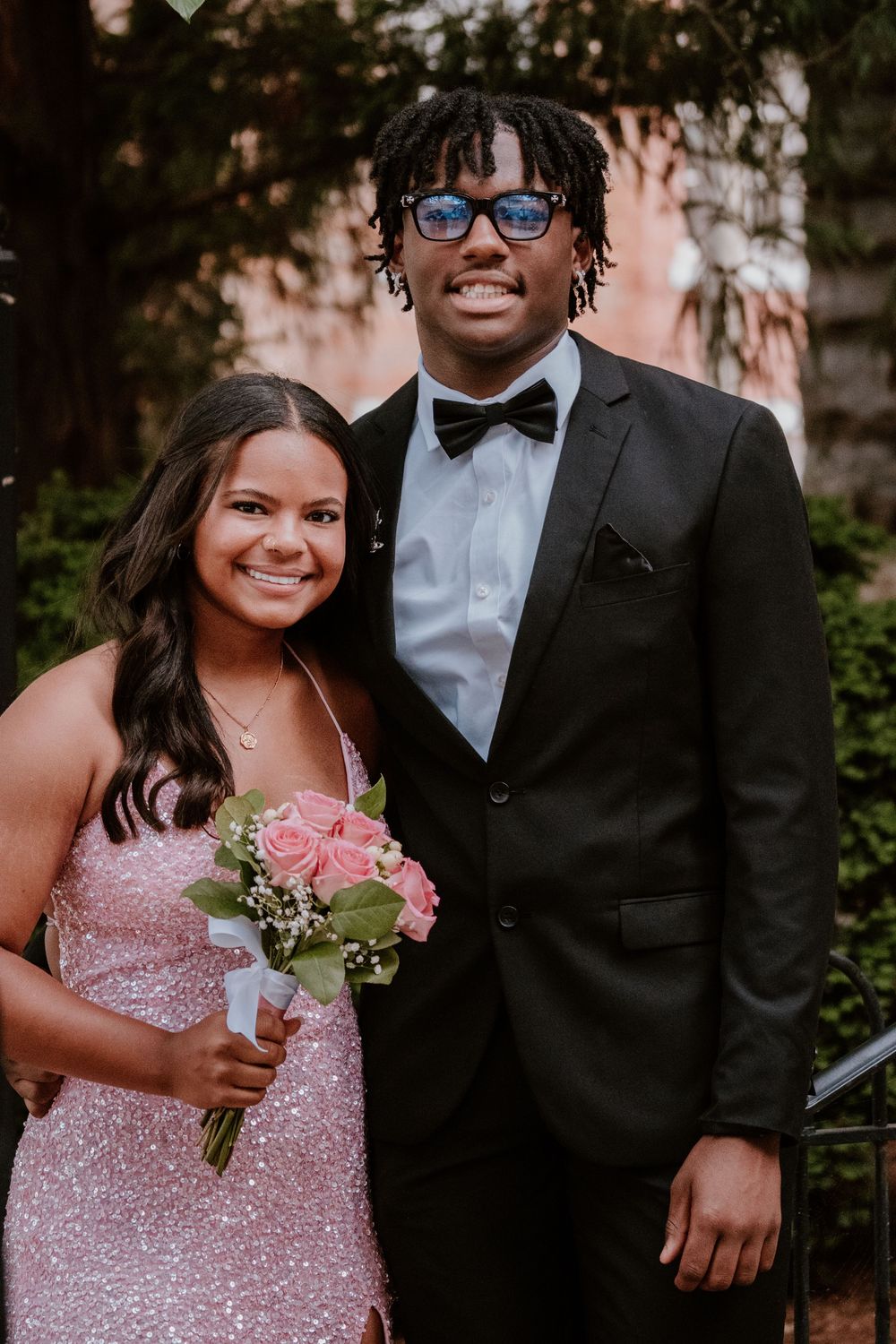 Prom couples pose together in formal wear with sparkly dresses and bow ties.